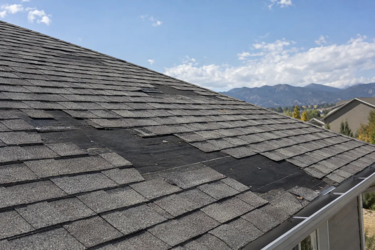Bare patch on a roof where wind tore away several shingles